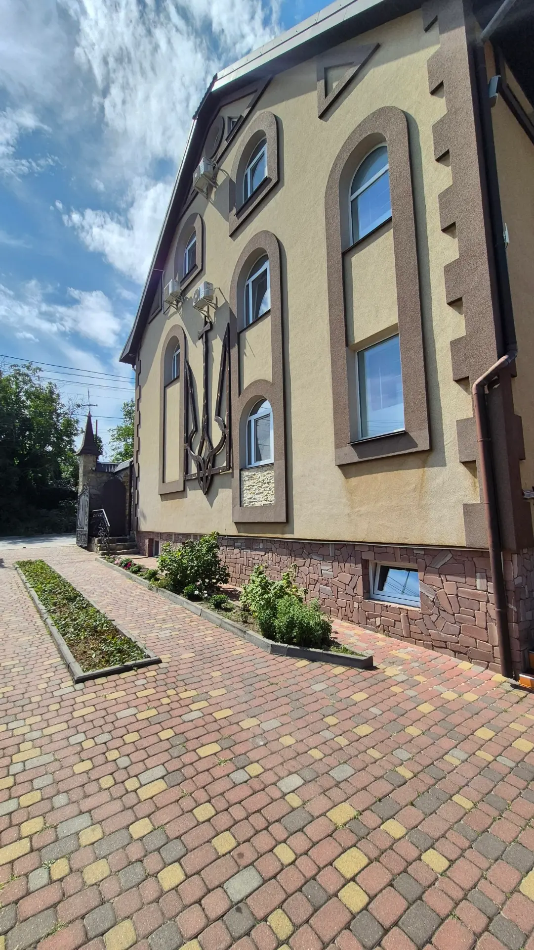 Територія садиби: клумби, брукований двір і фасад із гербом